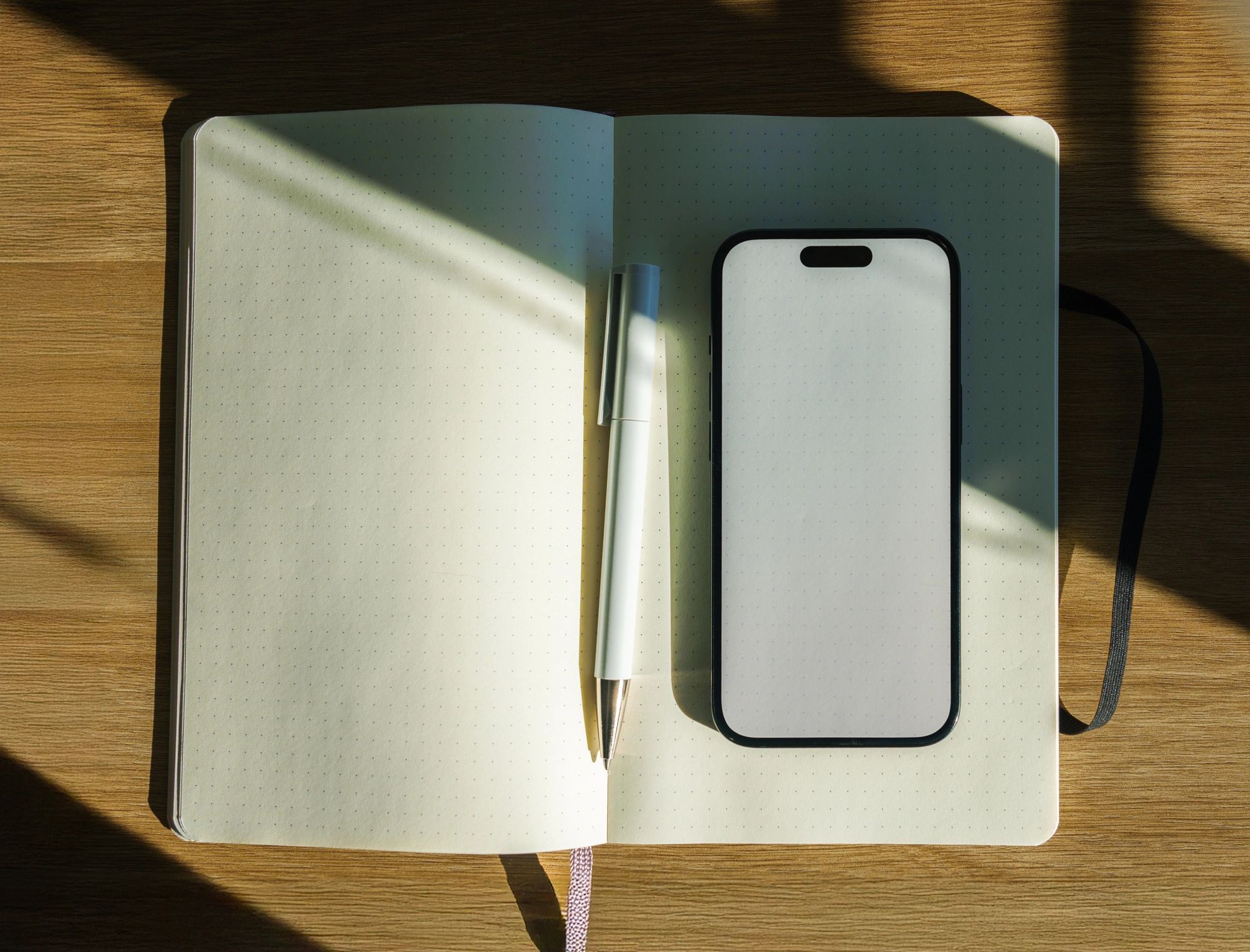 Notebook and smartphone on a wooden desk in natural sunlight